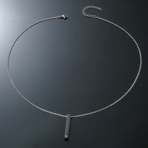 Detail of minimalist black pillar pendant necklace with silver chain and small rhinestone