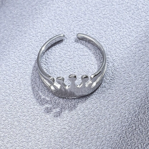 Detailed top view of an adjustable silver crown ring on a textured grey background