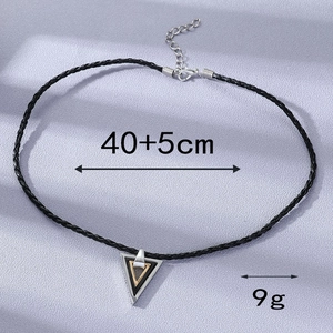 Dettaglio della collana con pendente a triangolo geometrico nei toni argento, nero e oro