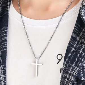 Minimalist silver titanium steel cross pendant necklace worn over a white t-shirt