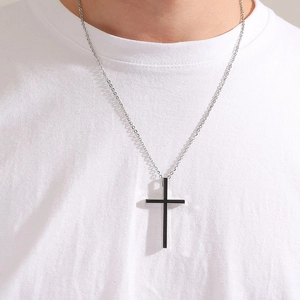 Macro shot of a black enamel cross pendant on a polished silver chain for men