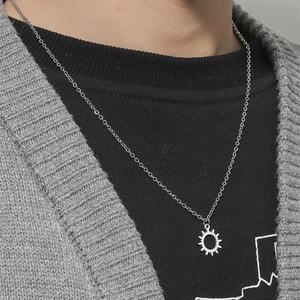 Detail shot of a silver hollow sun pendant necklace worn over a black shirt