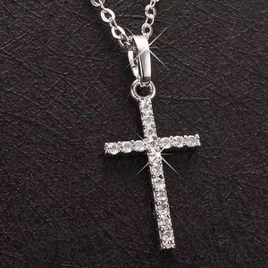 Classic silver-toned cross necklace with cubic zirconia stones on black leather texture