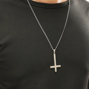 Pendentif croix inversée en argent poli sur une chaîne en acier inoxydable portée par un homme