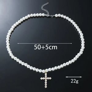 Détail macro du pendentif croix avec cristaux et élégante chaîne en perles blanches