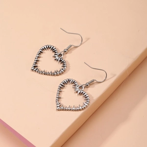 Gros plan de boucles d'oreilles cœur punk gothique Y2K avec détails d'épines acérées