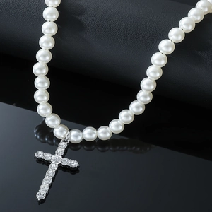 Vue macro d'un pendentif croix en cristal et collier de perles sur cuir noir