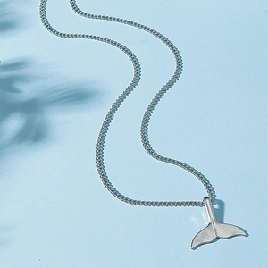 Minimalist silver mermaid tail necklace with polished dolphin pendant on light blue background