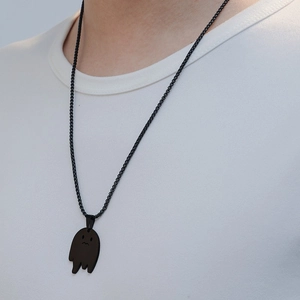 Gros plan d'un collier pendentif fantôme noir porté sur un t-shirt blanc pour hommes