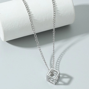 Minimalist silver geometric cube necklace with center zircon on a white cylinder stand