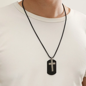 Close-up of minimalist black dog tag necklace with a silver cross pendant on a male model