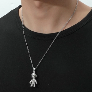 Close-up of a silver astronaut pendant necklace worn by a model on a black t-shirt