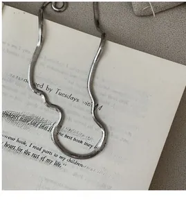 Detailed close-up of a silver flat snake chain necklace on a vintage book page