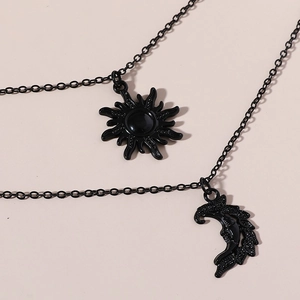 Detail of matte black layered necklace with celestial sun and moon face pendants