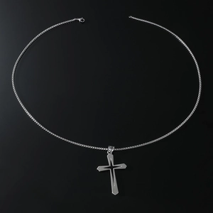 Vue détaillée du pendentif croix évidée en argent avec chaîne box polie sur fond noir intense