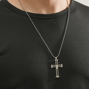Dettaglio del ciondolo a croce argento traforato con catena a sfere su maglia