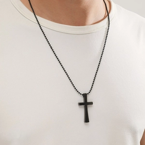Pendentif croix noir mat avec chaîne à billes porté par un mannequin masculin sur un t-shirt