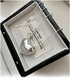 Macro shot of mirror-polished silver heart pendant on a delicate ball chain in a gift box