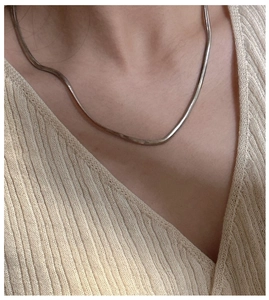 Close-up of a sleek S925 sterling silver flat snake chain necklace on a model