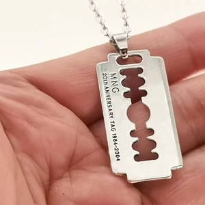Macro shot of silver razor blade pendant with anniversary engraving and cutout detail