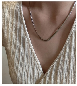 Close-up of minimalist S925 sterling silver flat snake chain worn on a V-neck sweater