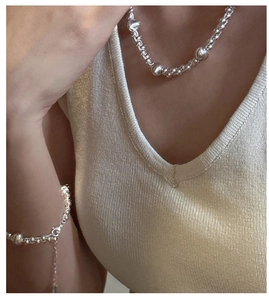 Polished silver beaded necklace and bracelet set worn on neck and wrist by a model