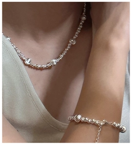 Detail of S925 sterling silver beaded necklace and bracelet set on model neckline