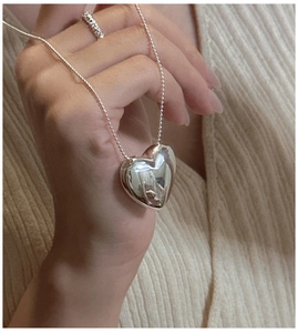 Macro shot of 3D polished heart pendant necklace and sparkling micro-pave diamond ring