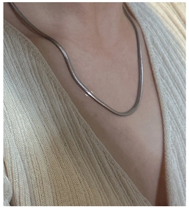 Close-up of a glossy S925 sterling silver flat snake chain necklace on a model's neck