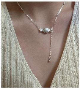 Dettaglio della collana con ciondolo a caramella in argento S925 su maglione beige