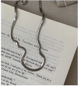 Detailed close-up of a silver flat snake chain necklace on an open vintage book