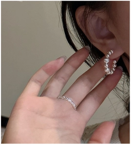 Detailed macro view of S925 sterling silver beaded C-shaped earrings and matching ring set