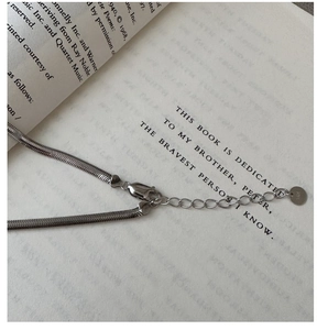 Macro shot of S925 sterling silver flat snake chain with lobster clasp on vintage book