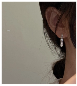 Side view of a silver beaded hoop earring worn by a model in a minimalist Korean style