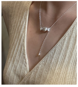 Dettaglio della collana in argento S925 a forma di caramella su un maglione lavorato a maglia