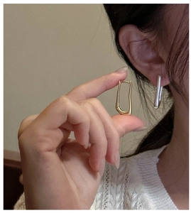 Dettaglio di orecchini a cerchio geometrici a U in oro e argento su una modella