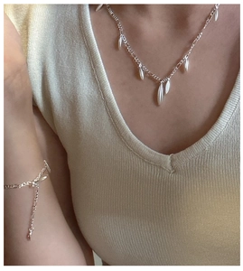 Detail view of S925 silver fringe necklace and bracelet set on a female model