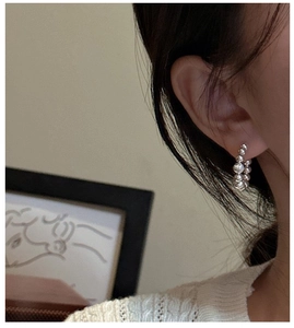 Close-up detail of S925 sterling silver beaded hoop earrings worn by a female model