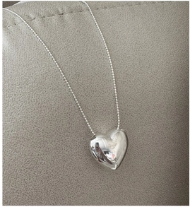 Macro shot of 3D polished heart pendant and silver ball chain with mirror finish texture