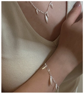 Close-up of matte silver drop pendant necklace and bracelet on a knitted surface