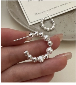 Detail of S925 sterling silver C-shaped beaded earrings with polished and brushed texture