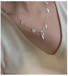 Detail of S925 silver Figaro chain necklace featuring polished leaf-shaped fringe charms