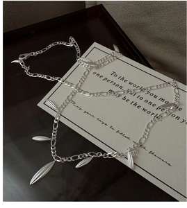 Macro detail of S925 sterling silver Figaro chain with matte leaf pendants