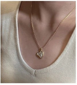 Detail of a minimalist gold heart pendant necklace with pearl inlay on a model