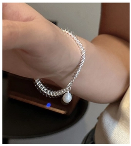 Gros plan du bracelet en argent sterling S925 orné d'un délicat pendentif en perle blanche