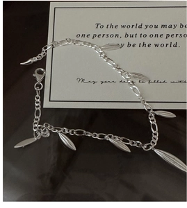 Detail view of S925 silver Figaro chain bracelet with olive-shaped drop charms and lobster clasp