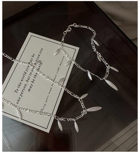 Detail of S925 sterling silver figaro chain with textured leaf pendants on black tray