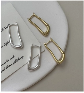 Dettaglio orecchini a U ondulati in argento S925 con finiture opache in oro e argento