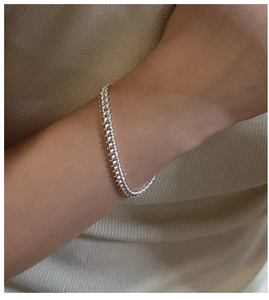 Gros plan d'un bracelet en argent S925 à maillons gourmette porté au poignet d'une femme