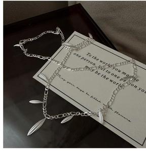 Detailed shot of S925 silver figaro chain bracelet with olive leaf charms on display